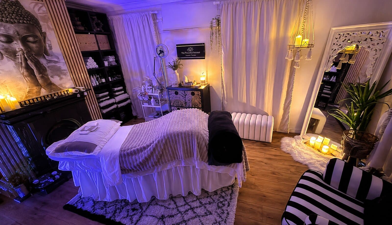 Stacey’s candlelit treatment room at The Peace Retreat, with a draped massage table, warm candlelight, a tall mirror and soft furnishings